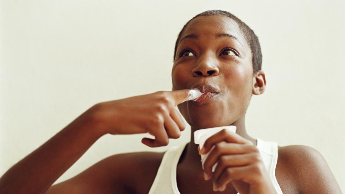 a woman eating yoghurt as it is a good food for vaginal health